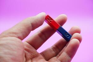 hand holding a bar magnet isolated on a purple background photo