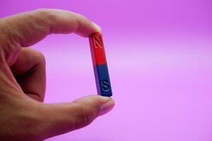 hand holding a bar magnet isolated on a purple background photo