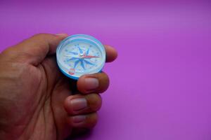 hand holding a compass isolated on a purple background photo