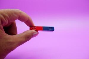hand holding a bar magnet isolated on a purple background photo