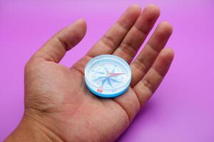 hand holding a compass isolated on a purple background photo