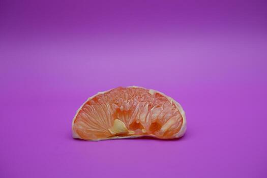 a slice of grapefruit isolated on a purple background. grapefruit that has been peeled until the grain of the orange is visible photo