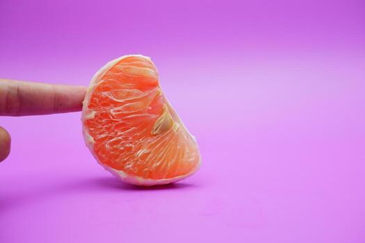 a slice of grapefruit isolated on a purple background. grapefruit that has been peeled until the grain of the orange is visible photo