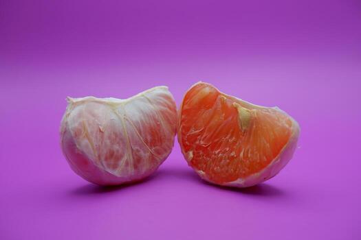 2 grapefruit isolated on purple background. 2 pieces of grapefruit that have been peeled until the grain of the orange is visible photo