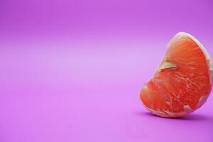 a slice of grapefruit isolated on a purple background. grapefruit that has been peeled until the grain of the orange is visible photo
