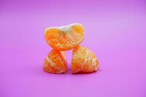 oranges that have been peeled and divided into several parts. orange isolated on purple background photo