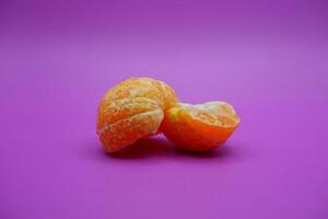 oranges that have been peeled and divided into several parts. orange isolated on purple background photo