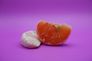 2 grapefruit isolated on purple background. 2 pieces of grapefruit that have been peeled until the grain of the orange is visible photo
