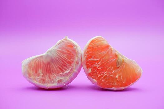 2 grapefruit isolated on purple background. 2 pieces of grapefruit that have been peeled until the grain of the orange is visible photo