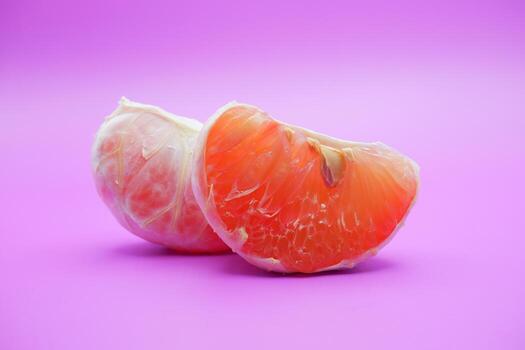 2 grapefruit isolated on purple background. 2 pieces of grapefruit that have been peeled until the grain of the orange is visible photo
