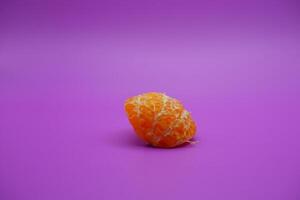 oranges that have been peeled and divided into small parts. orange isolated on purple background photo