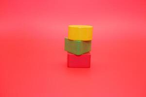 colorful wooden toys isolated red background. wooden toys shaped like triangles, squares and circles. photo