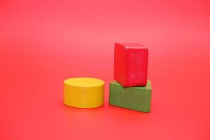colorful wooden toys isolated red background. wooden toys shaped like triangles, squares and circles. photo
