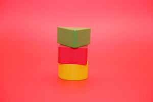 colorful wooden toys isolated red background. wooden toys shaped like triangles, squares and circles. photo