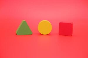 colorful wooden toys isolated red background. wooden toys shaped like triangles, squares and circles. photo