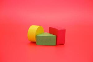 colorful wooden toys isolated red background. wooden toys shaped like triangles, squares and circles. photo