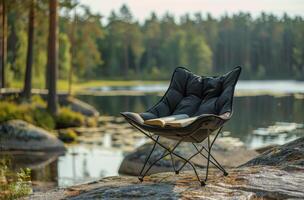 Black Folding Camp Chair Near Lake With Book in the Forest photo