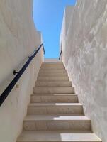 White Stone Staircase Leading Up to a Blue Sky View in a Modern Building photo