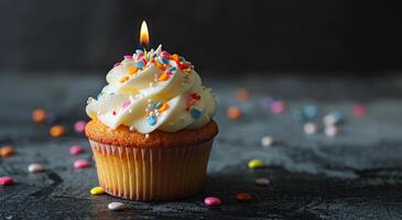 Single Birthday Cupcake With Sprinkles and Lit Candle on a Dark Background photo