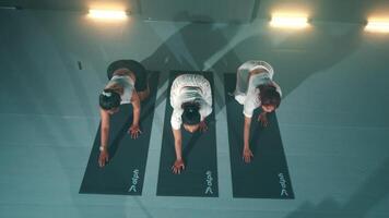 Top view of three people practicing yoga in a studio video