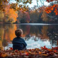 Young Boy Contemplating Autumn Colors by a Lake photo