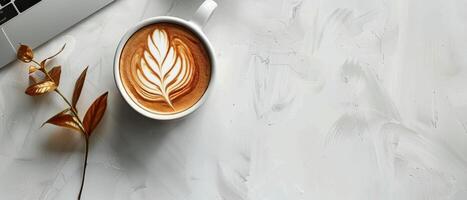 A Cup of Latte With Leaf Art on a White Tabletop photo
