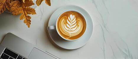 A Cup of Latte With Leaf Art on a White Tabletop photo