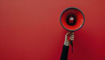 Person Holding Red Megaphone Against Red Background photo