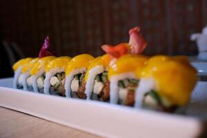 Sushi rolls are rotated in package after delivery. Philadelphia roll in sushi set close up. Traditional Japanese food. Japanese kitchen with sea food. Taking one sushi roll from set using chopsticks. photo