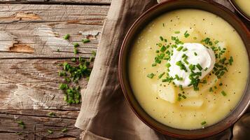 A bowl of creamy potato soup garnished with chives and sour cream photo