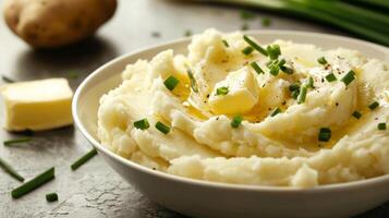 A bowl of creamy mashed potatoes topped with butter and chives photo