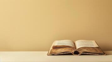 An open book lies on a white surface, with a tan wall behind it photo