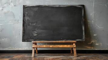 Black chalkboard on wooden easel stands by grey wall photo