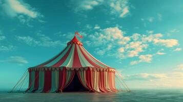 A red and white striped circus tent stands on a beach under a blue sky photo