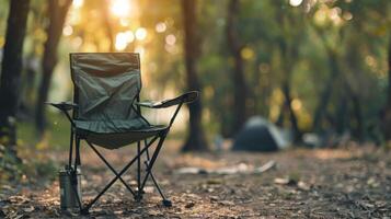 A lone camping chair sits in a forest clearing at sunset photo