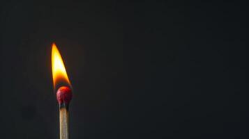 A close-up of a lit matchstick against a dark background photo