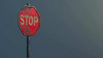 A weathered red stop sign against a grey sky photo