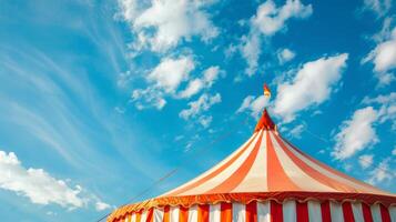 The red and white striped top of a circus tent against a blue sky photo