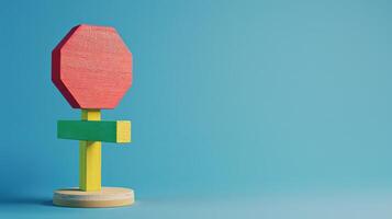 A red, yellow, and green wooden stop sign toy stands on a blue background photo