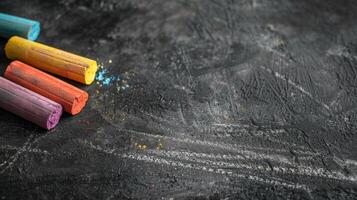 Colorful chalk sticks on a black chalkboard background photo