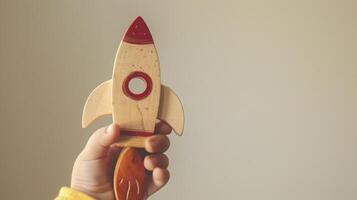 A childs hand holds a wooden rocket toy photo
