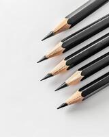 Five black pencils lie on a white surface, ready for drawing or writing photo