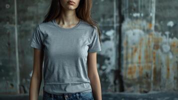 A woman model wears a blank t-shirt with space for text against a distressed concrete wall photo