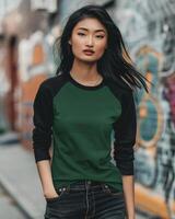 A woman wearing a green and black raglan t-shirt stands in an urban setting photo