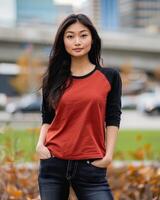 A woman stands in an urban setting, wearing a red and black raglan shirt photo