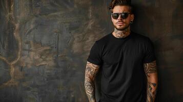 A tattooed man in a blank t-shirt stands against a textured wall photo