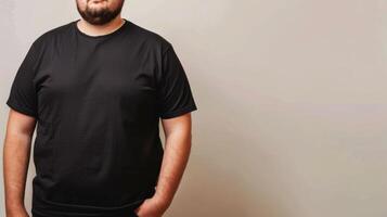 A man wearing a plain black t-shirt stands against a simple, off-white backdrop photo