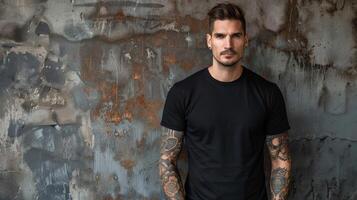 A man wearing a blank black t-shirt stands confidently against a textured wall photo