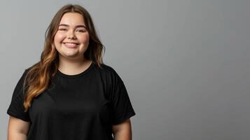 A smiling woman in a black t-shirt stands against a grey backdrop photo