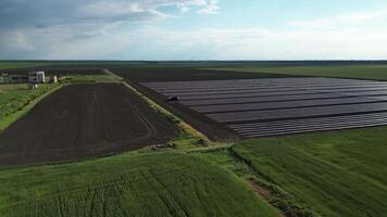 Aerial view of a large farm field with black plastic mulch covering a portion of the field. Green crops are growing in other areas of the field video